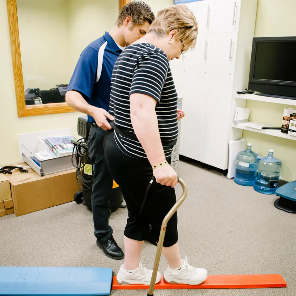 A therapist supports a patient practicing a step exercise at Cancer Rehabilitation Centers