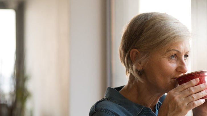 A woman reflecting on her treatment while having a cup of coffee
