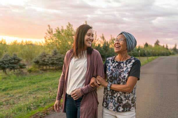 Patient advocate walking with patient at sunset.